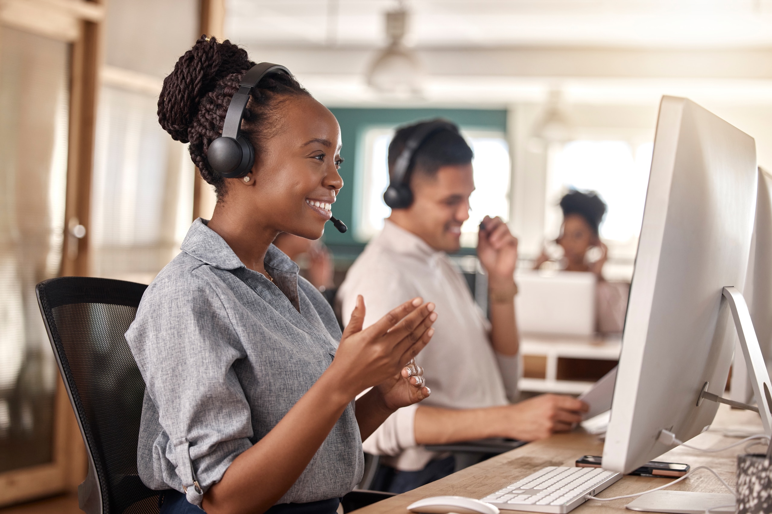 A call center agent cheerfully conducts an outbound call in a busy outgoing call center.