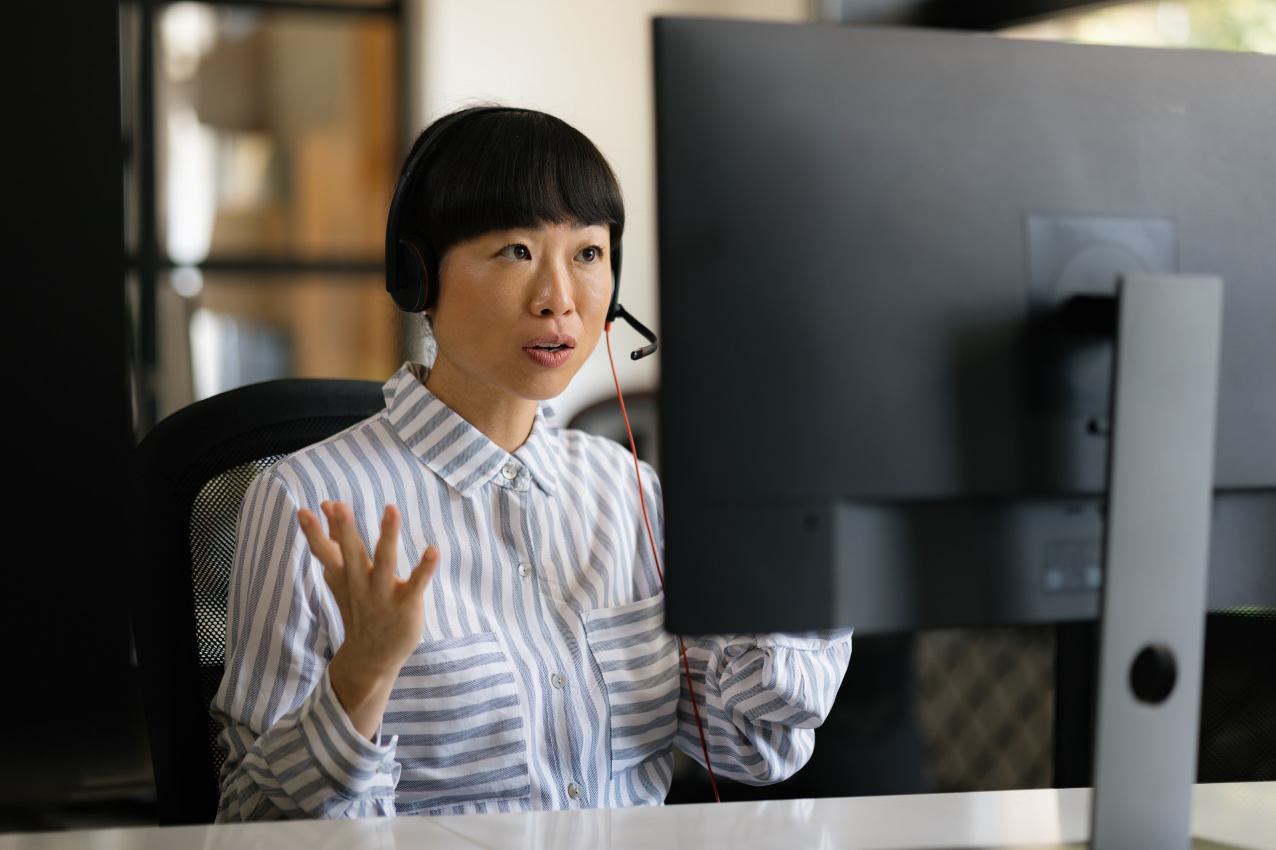 An outbound call agent conducts a sales call at her desk in a call center