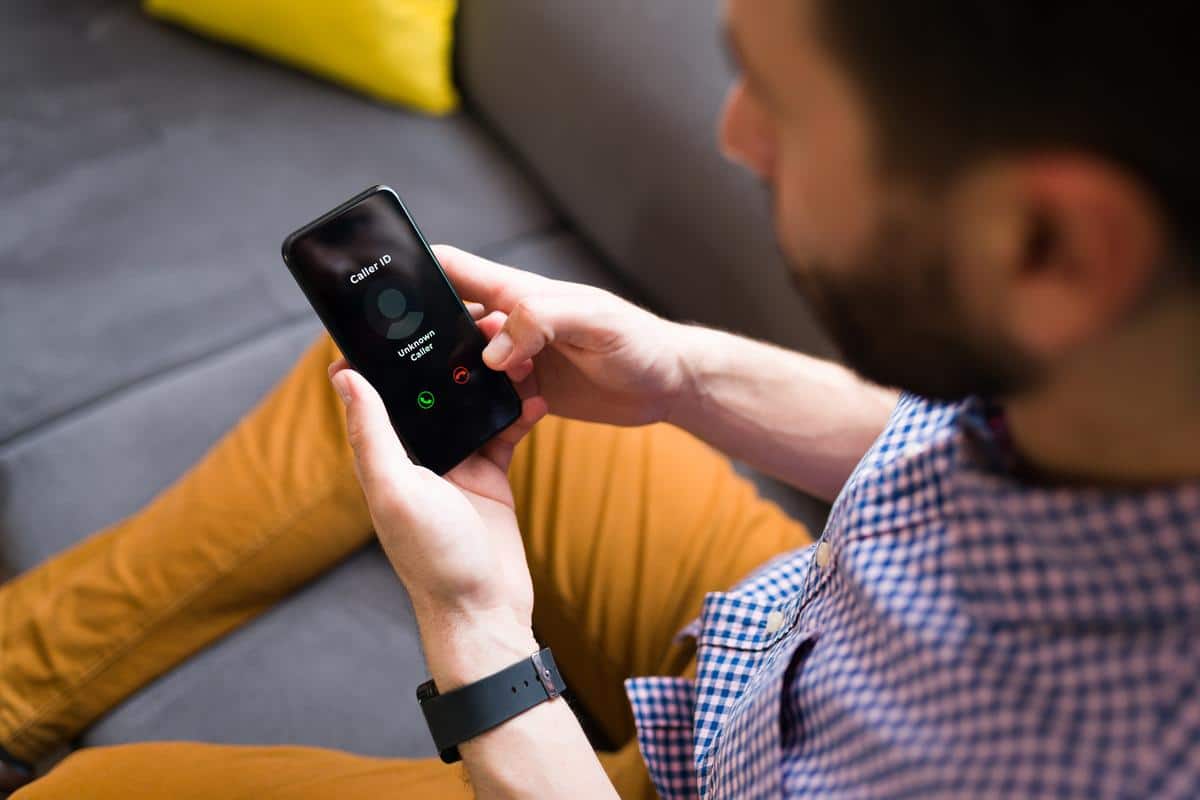 A man sees an incoming call on his smartphone with an unknown caller. Caller ID is different from ANI phone numbers. 