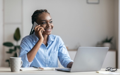 woman talking on the phone smiling while also on laptop