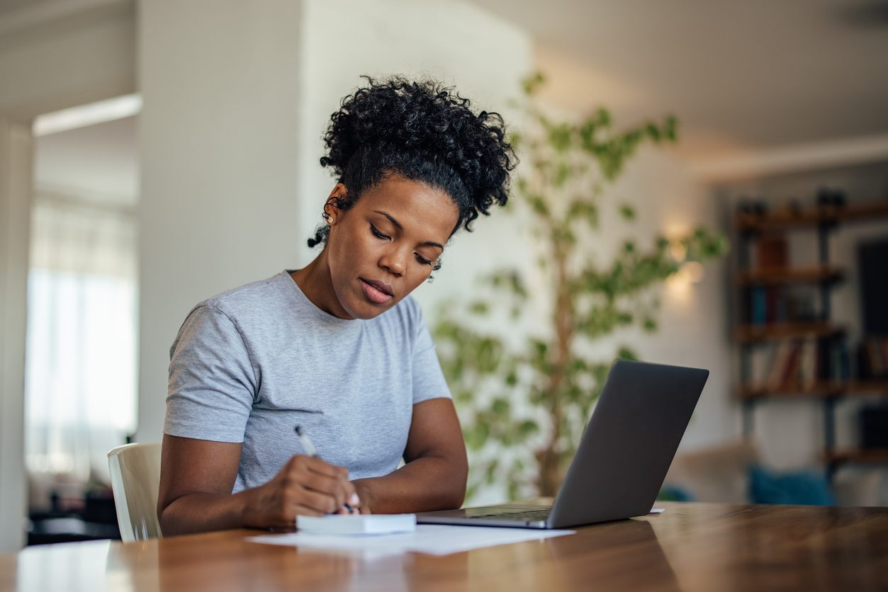 writing down with laptop in front of her