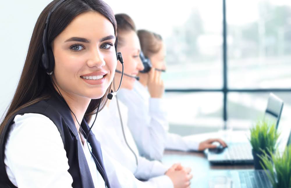 Female call center agents provide customer service through their telephone headsets.