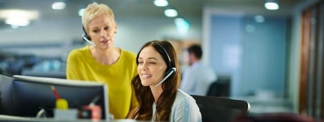 female customer service agent and female supervisor listening empathetically to a customer while sitting at a desk