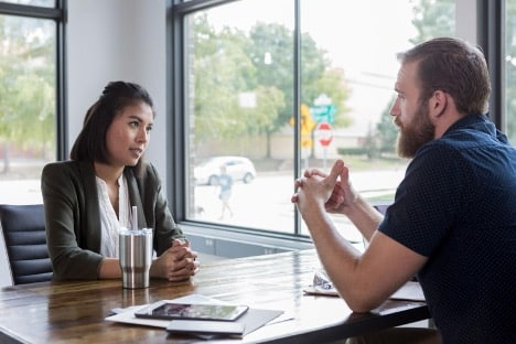 female professional sitting at a desk discussing a complaint with a customer