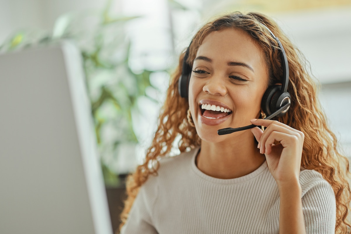 a call center agent happily talking on a headset as part of a customer care outsourcing team