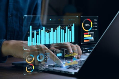 A person’s hands seen typing on a laptop, generating pie charts, graphs, and other analytical tools.