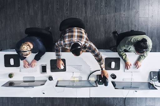 n aerial shot of three call center agents offering a variety of services to customers in an inbound call center.