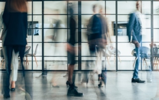 A bustling office hallway with employees rushing past in a blur.