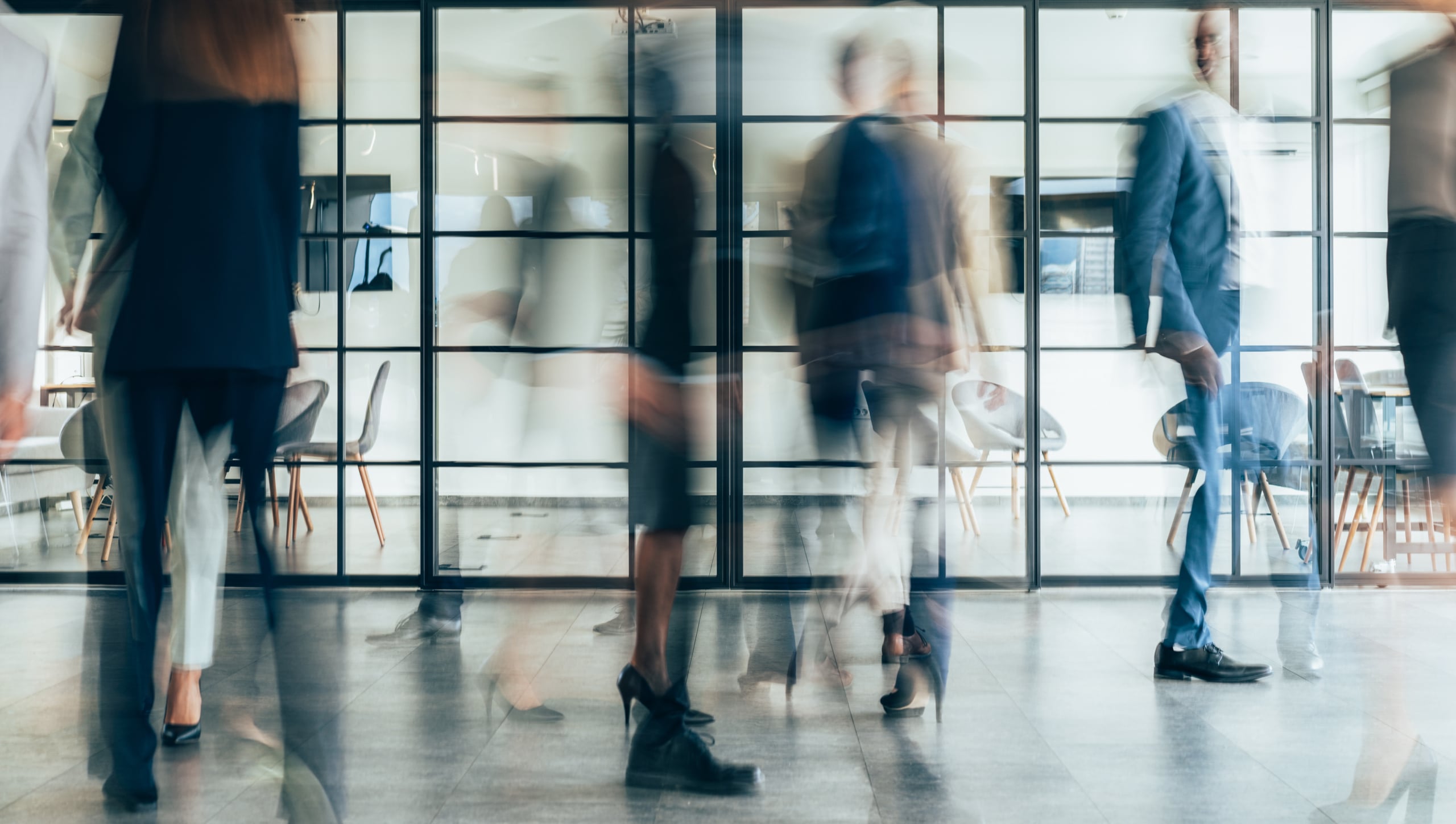 A bustling office hallway with employees rushing past in a blur.