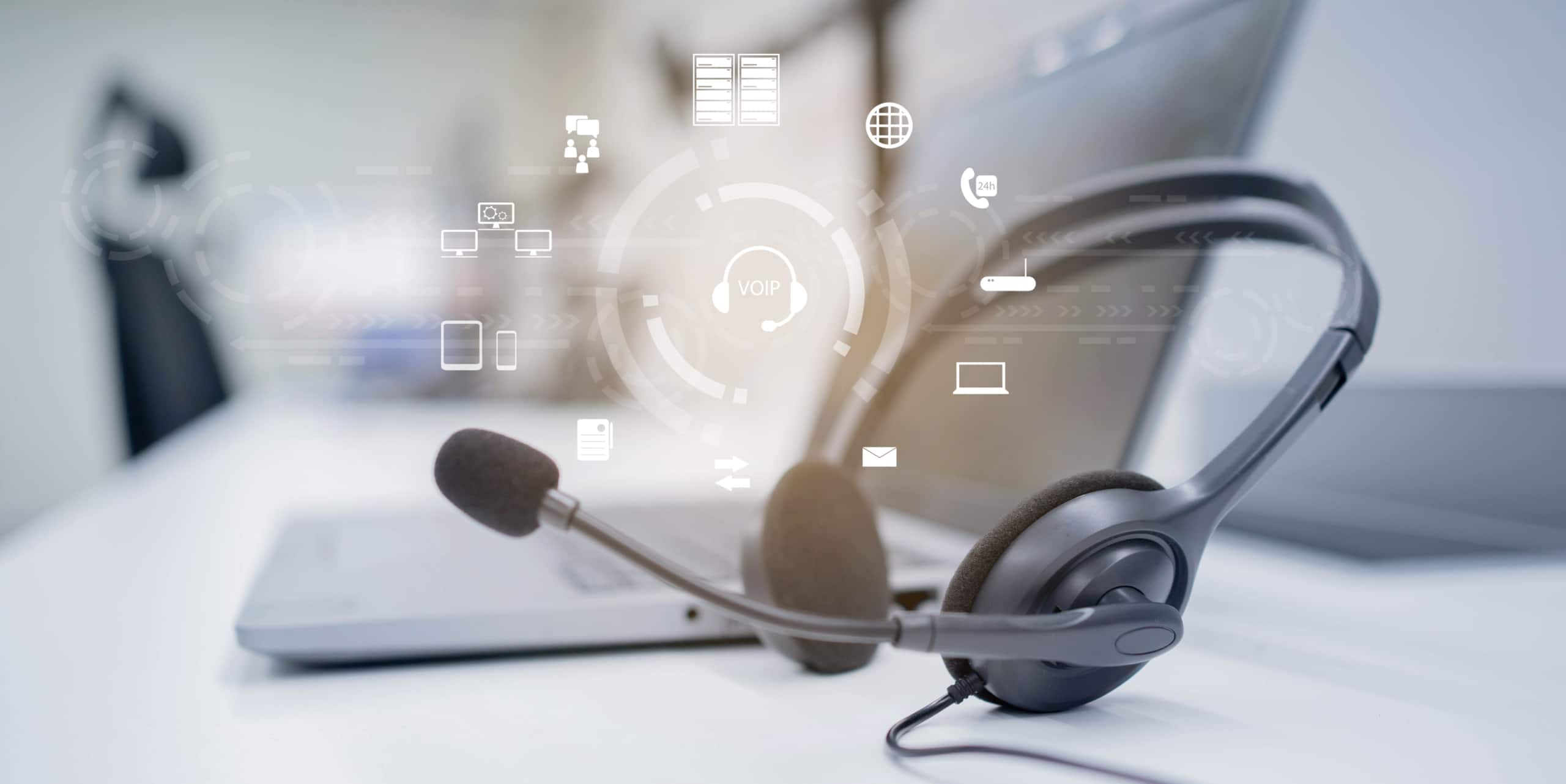 A laptop with a headset sitting on a desk, with an abstract visualization of cloud-based call center features superimposed over the image.