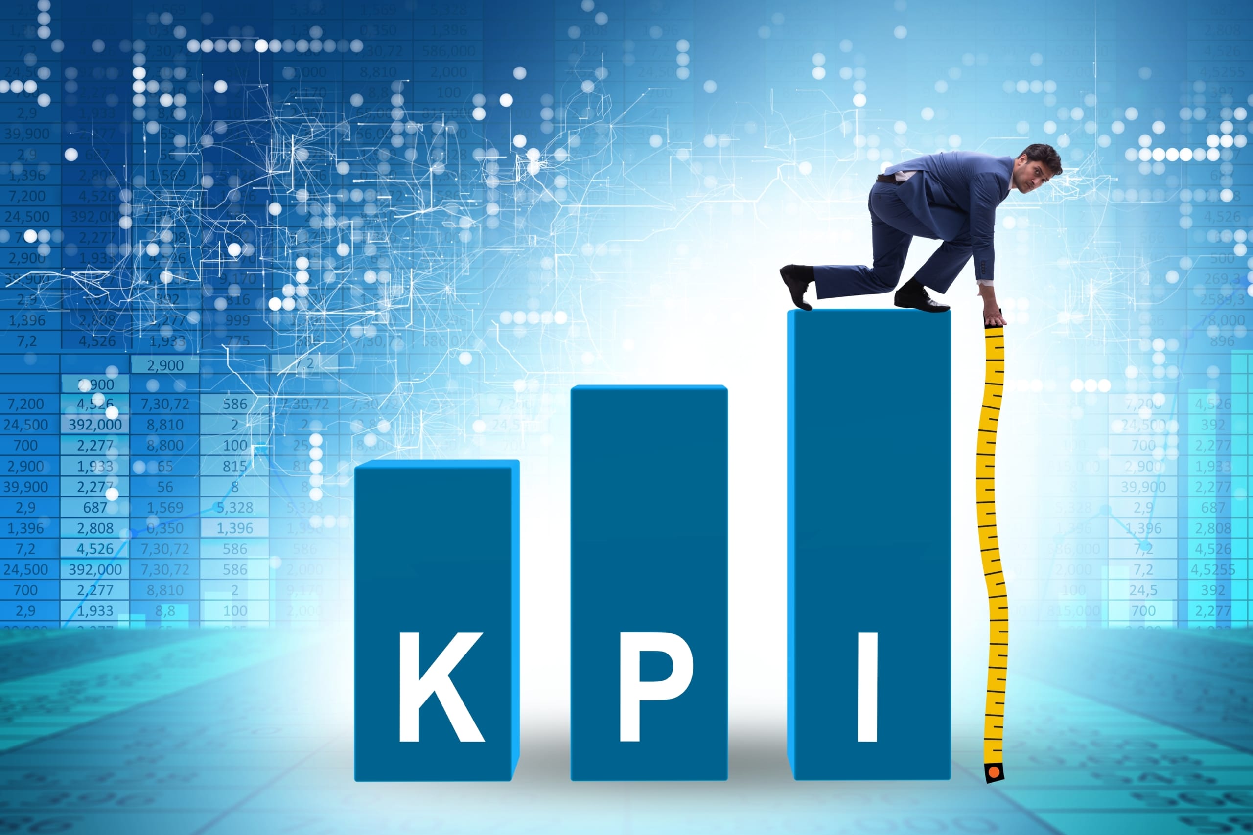 Businessman perched on KPI pillar labeled ‘I’ with measuring tape