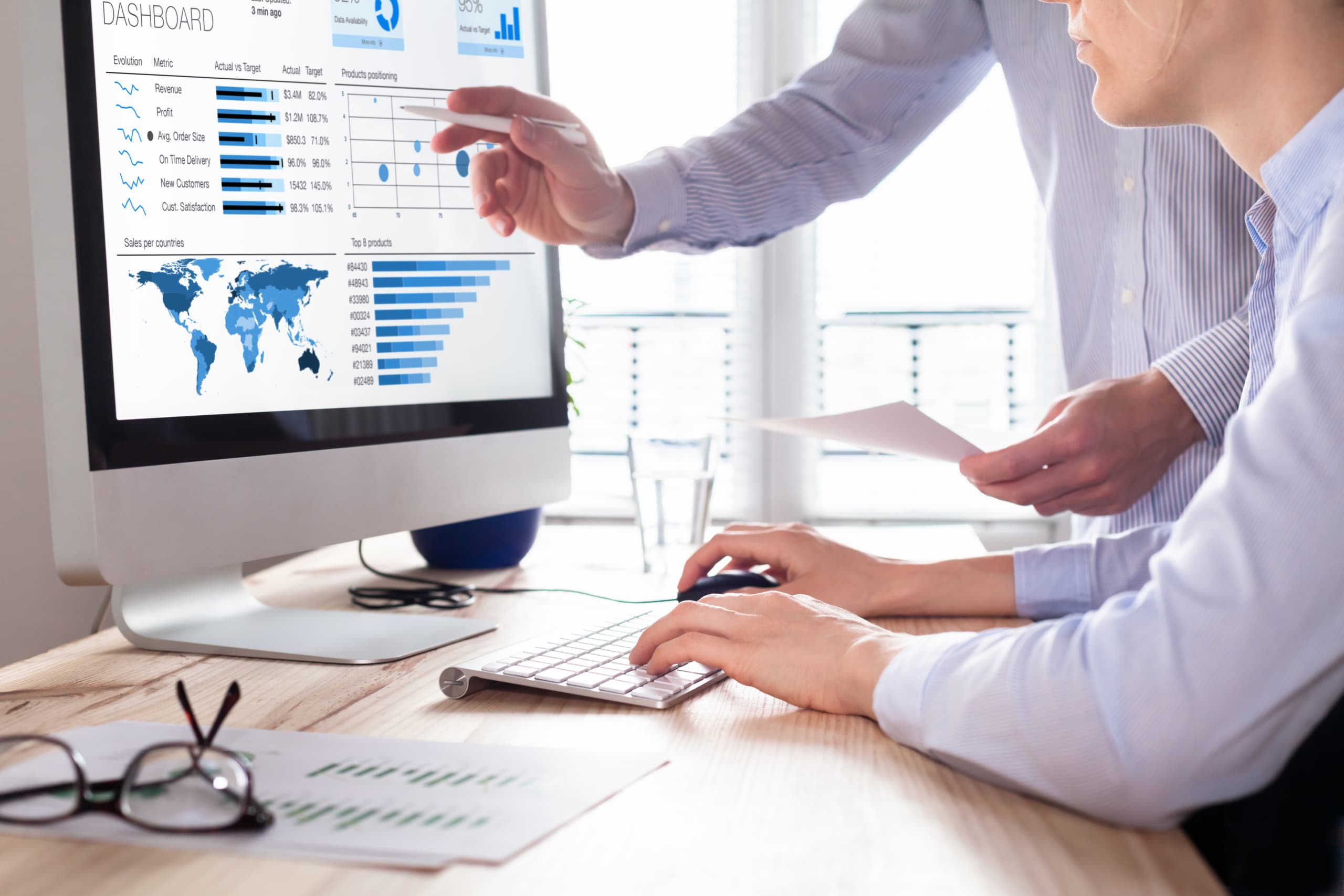 Two workers reviewing analytics on a desktop