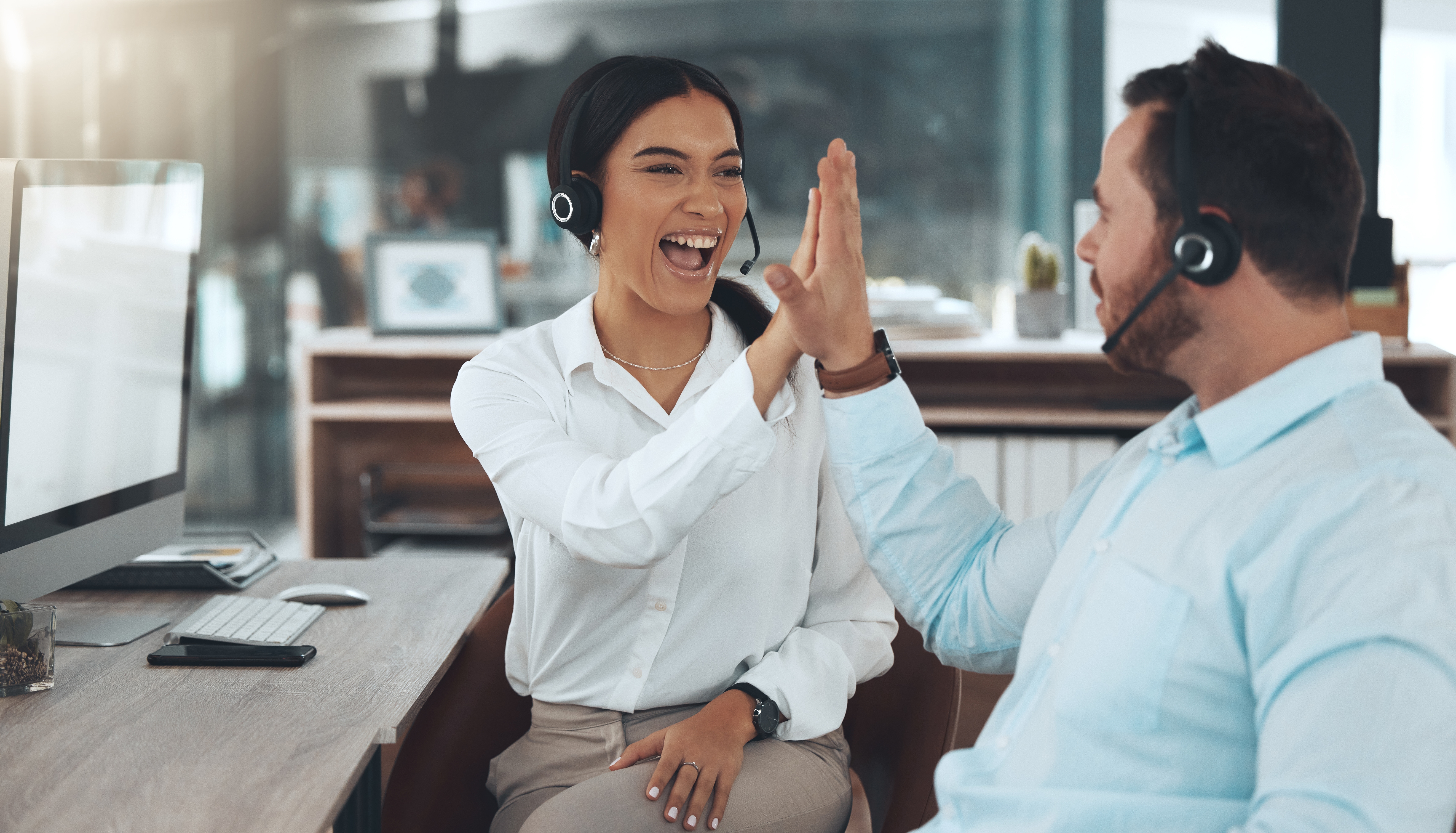 Two call center agents high-fiving each other