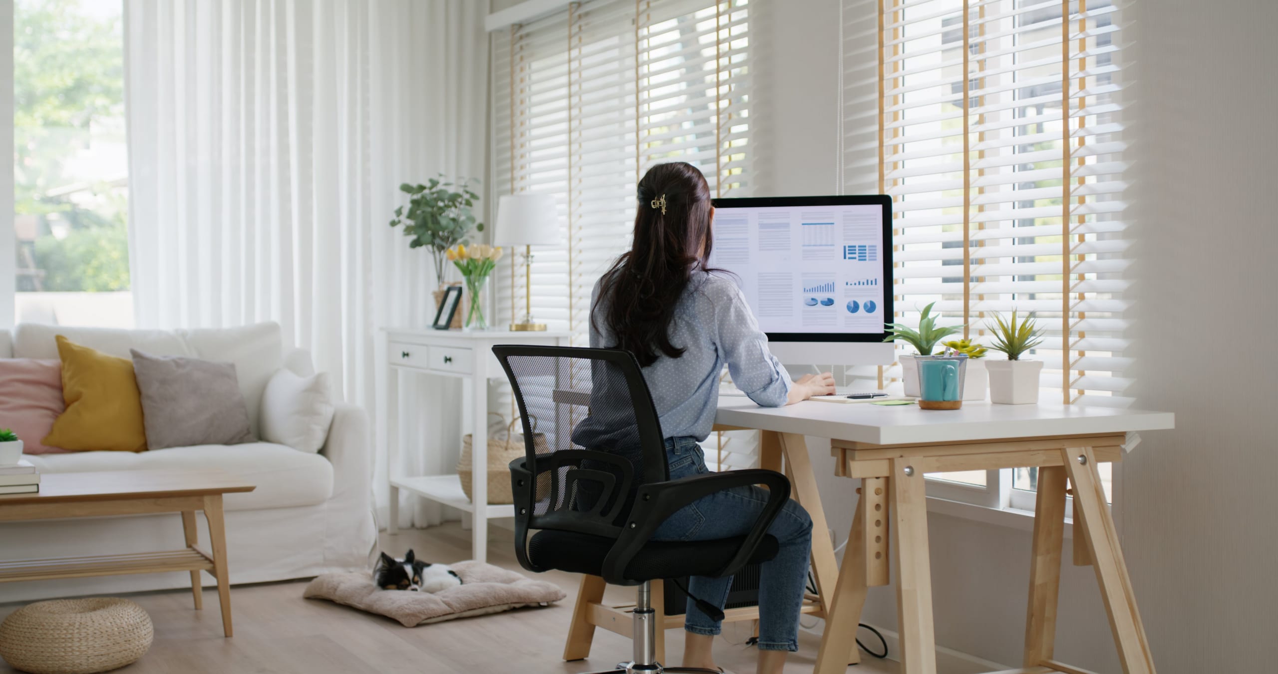 A woman working at her computer in a sunlit home office.]