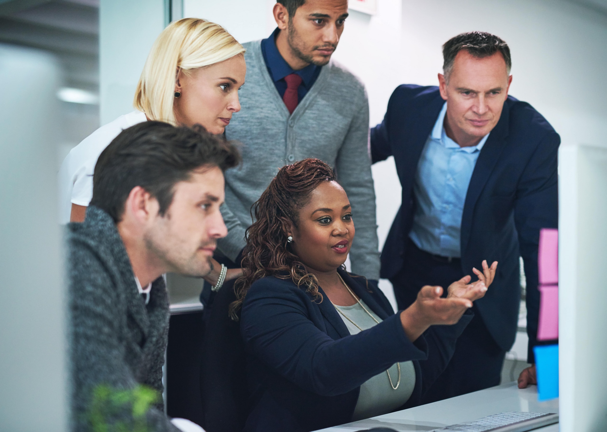 A diverse group of professionals looking at a computer screen together.