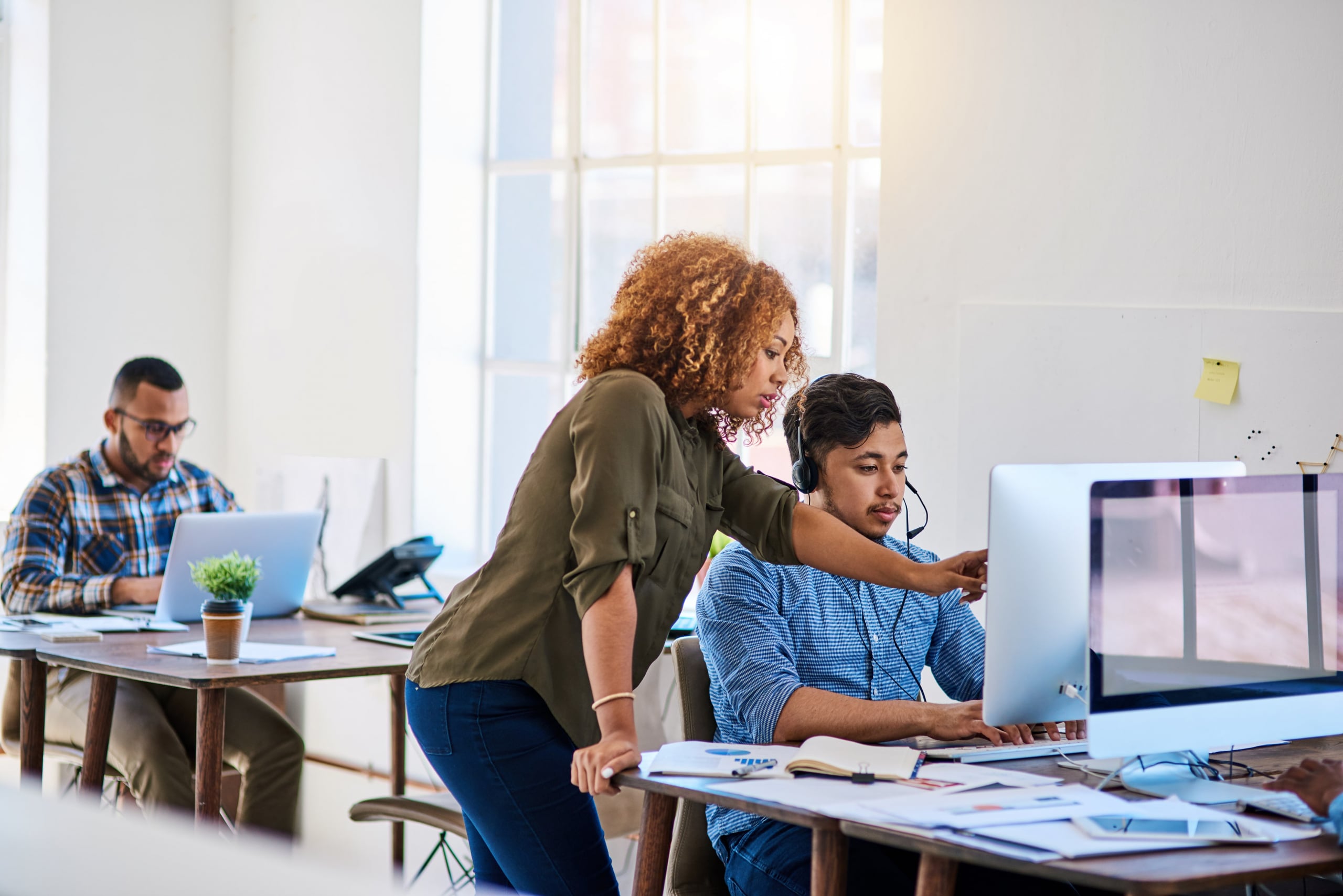 A contact center manager trains an agent on the various tools they will use for omnichannel services.