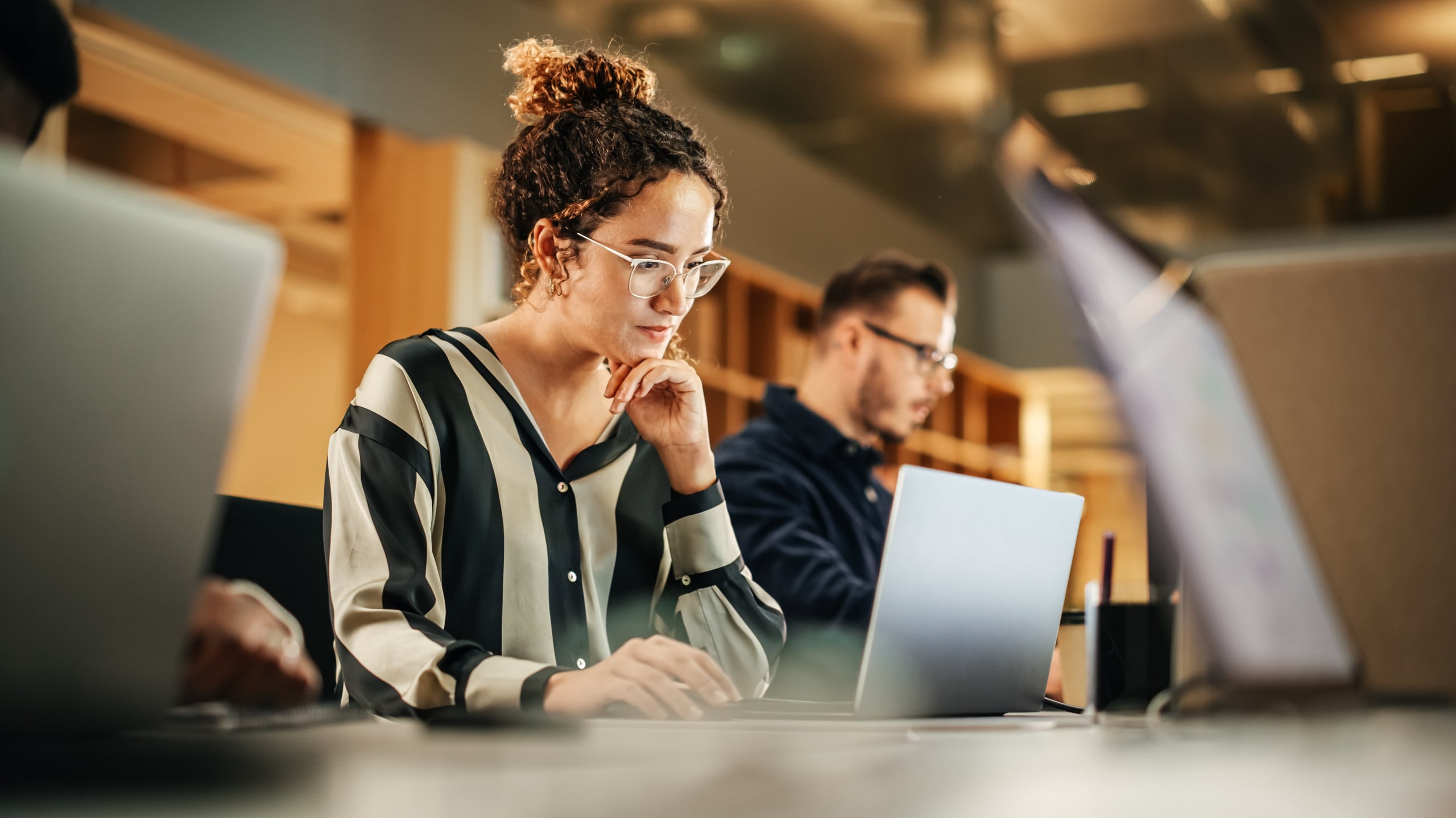 Portrait of a Hispanic woman working on computer in a modern bright office.
