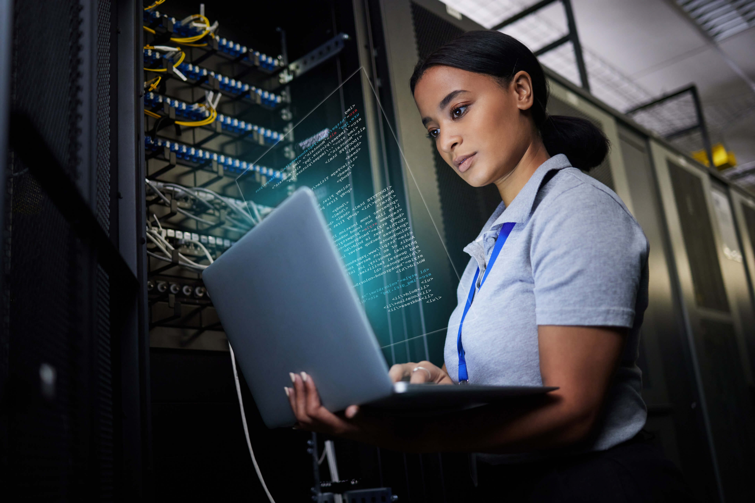 Female IT worker on computer by servers diagnosing IT server problem