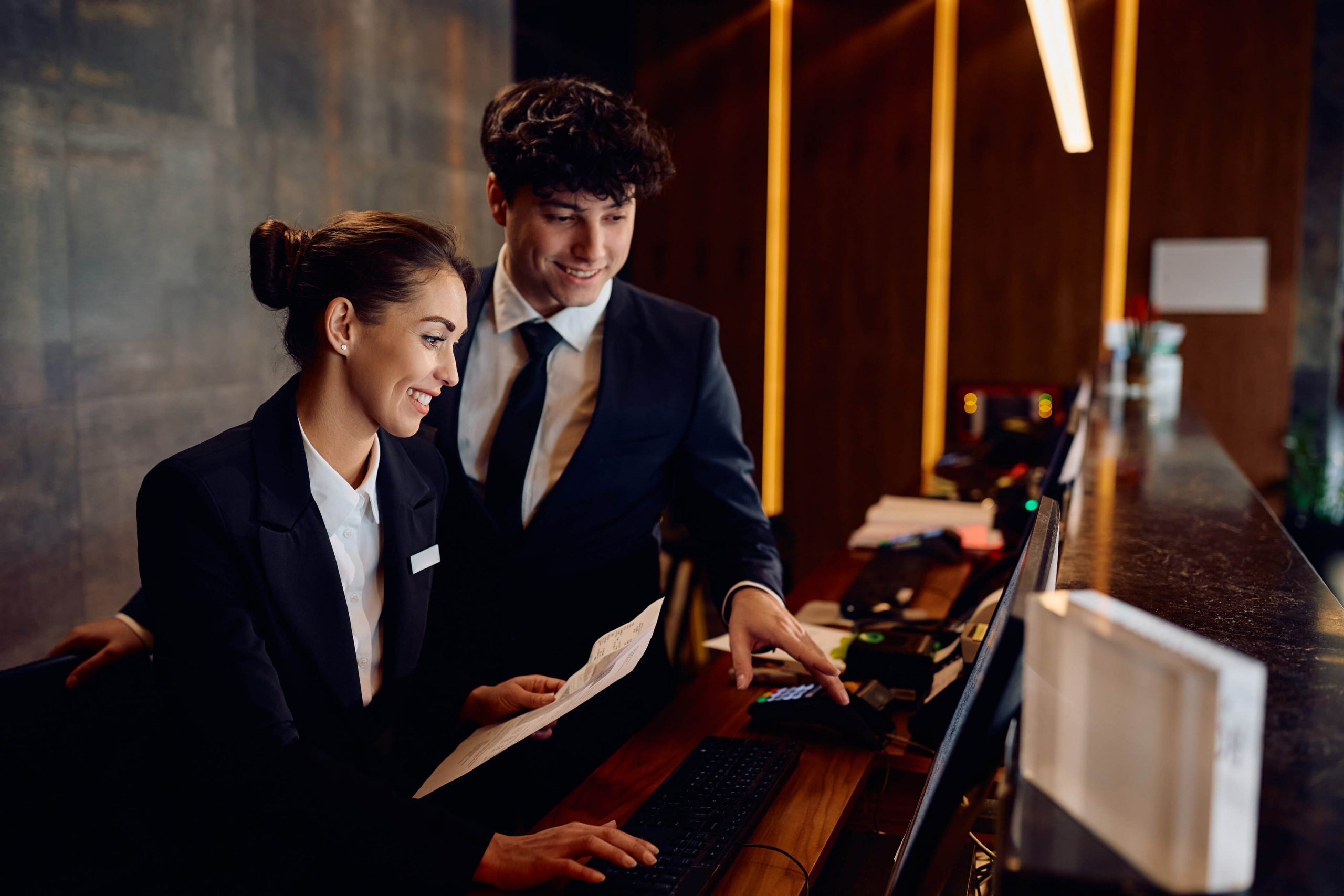 Two hotel coworkers at the front desk looking at appointments on a computer
