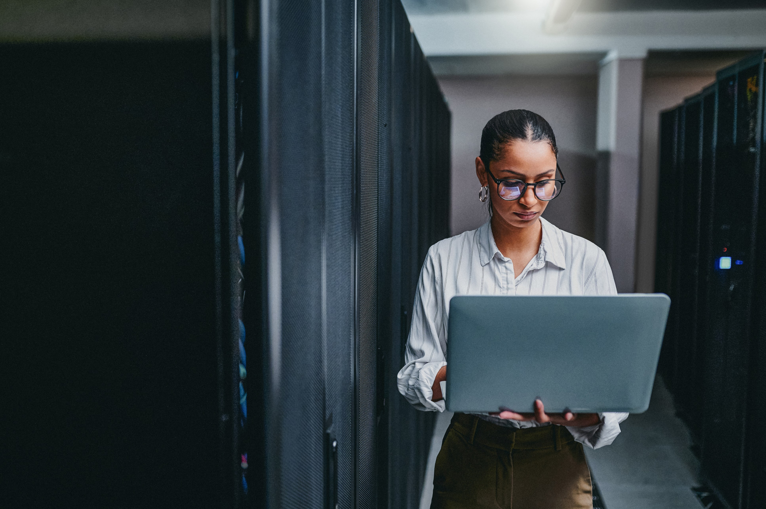 African American woman with her laptop standing in a server room