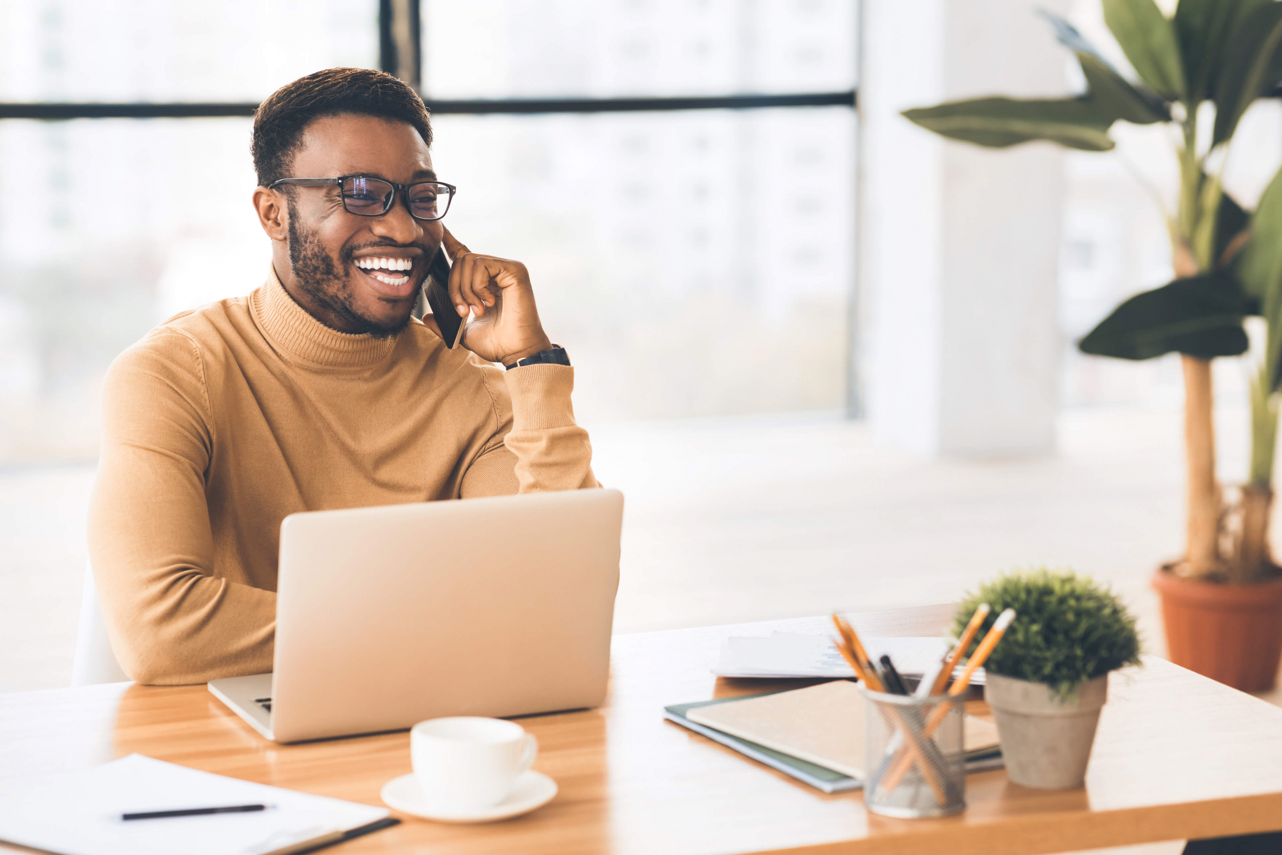Young african-american man on the phone sitting at his computer