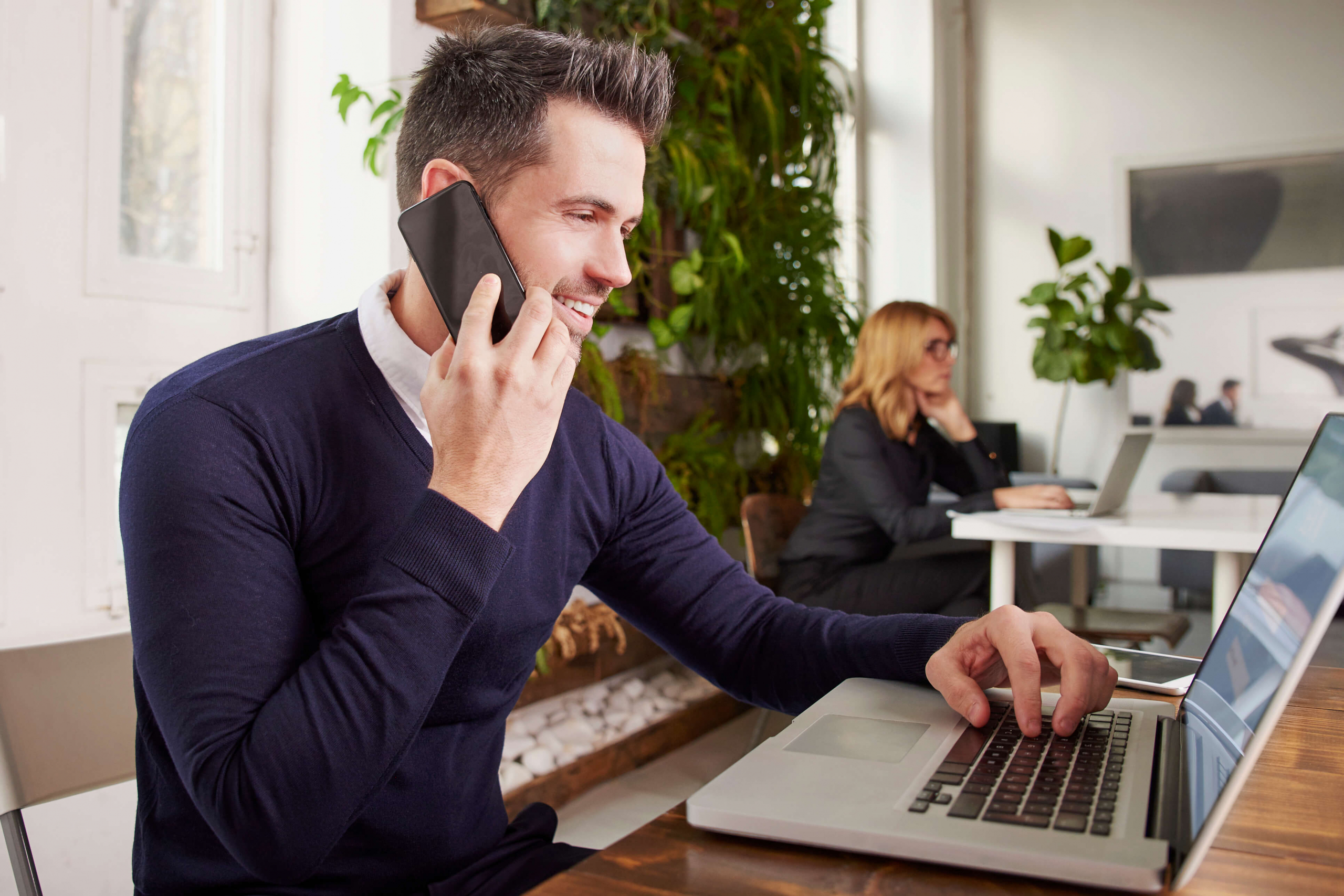 Young man talking on his cell phone while on his laptop