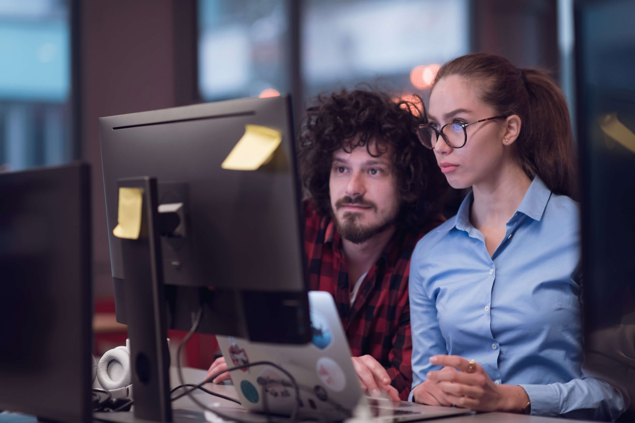 Male and female co-workers looking at a computer screen