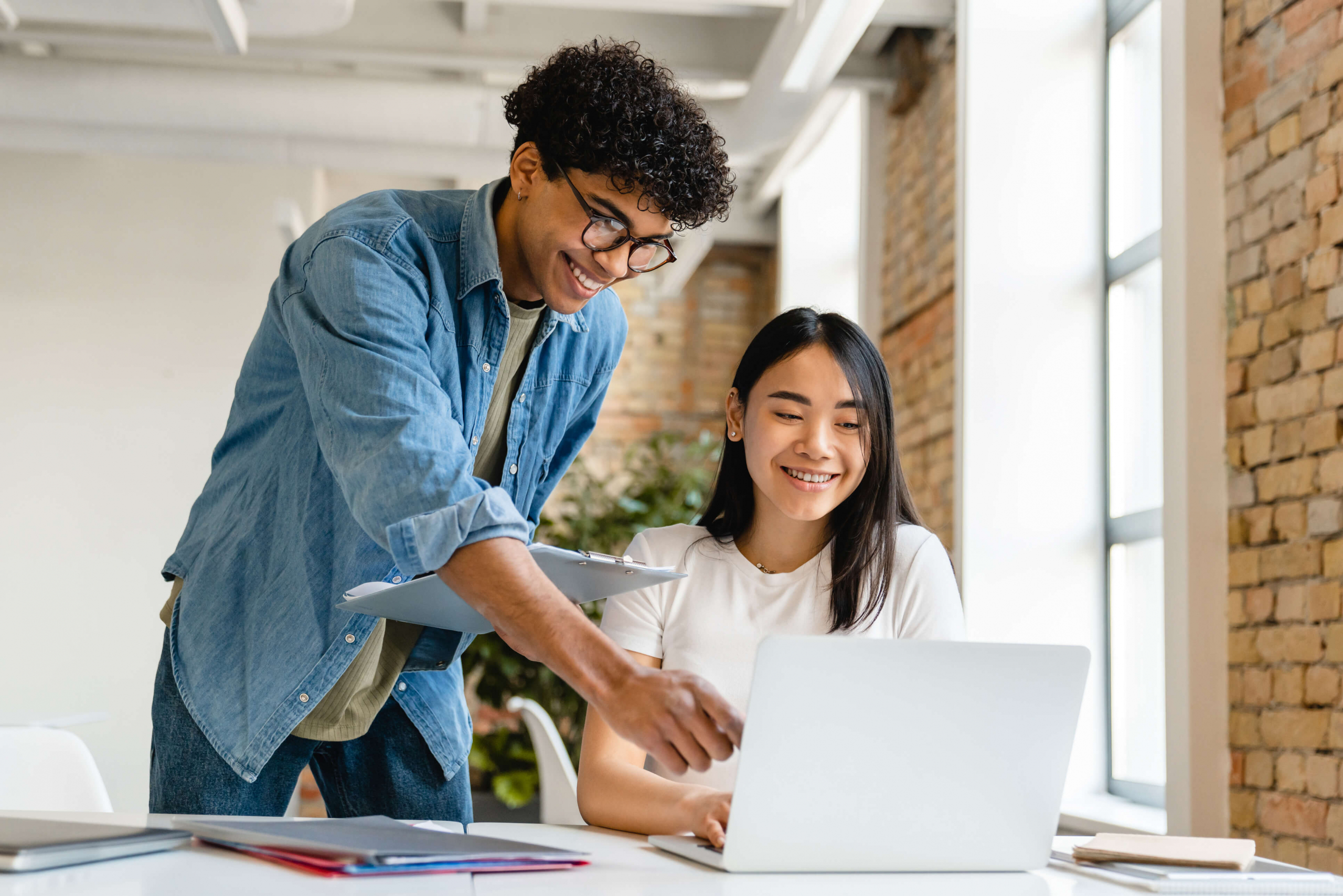 Two co-workers smiling pointing at a laptop screen