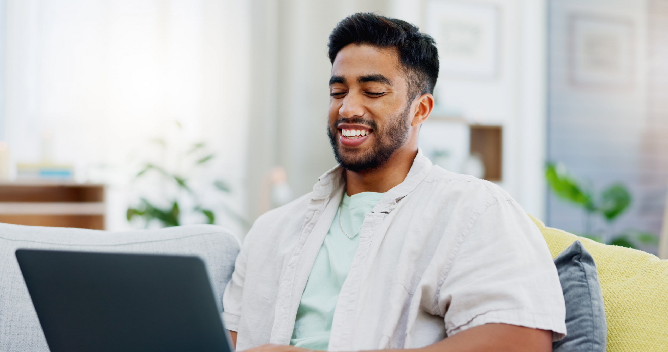 young male on his couch chatting on his computer
