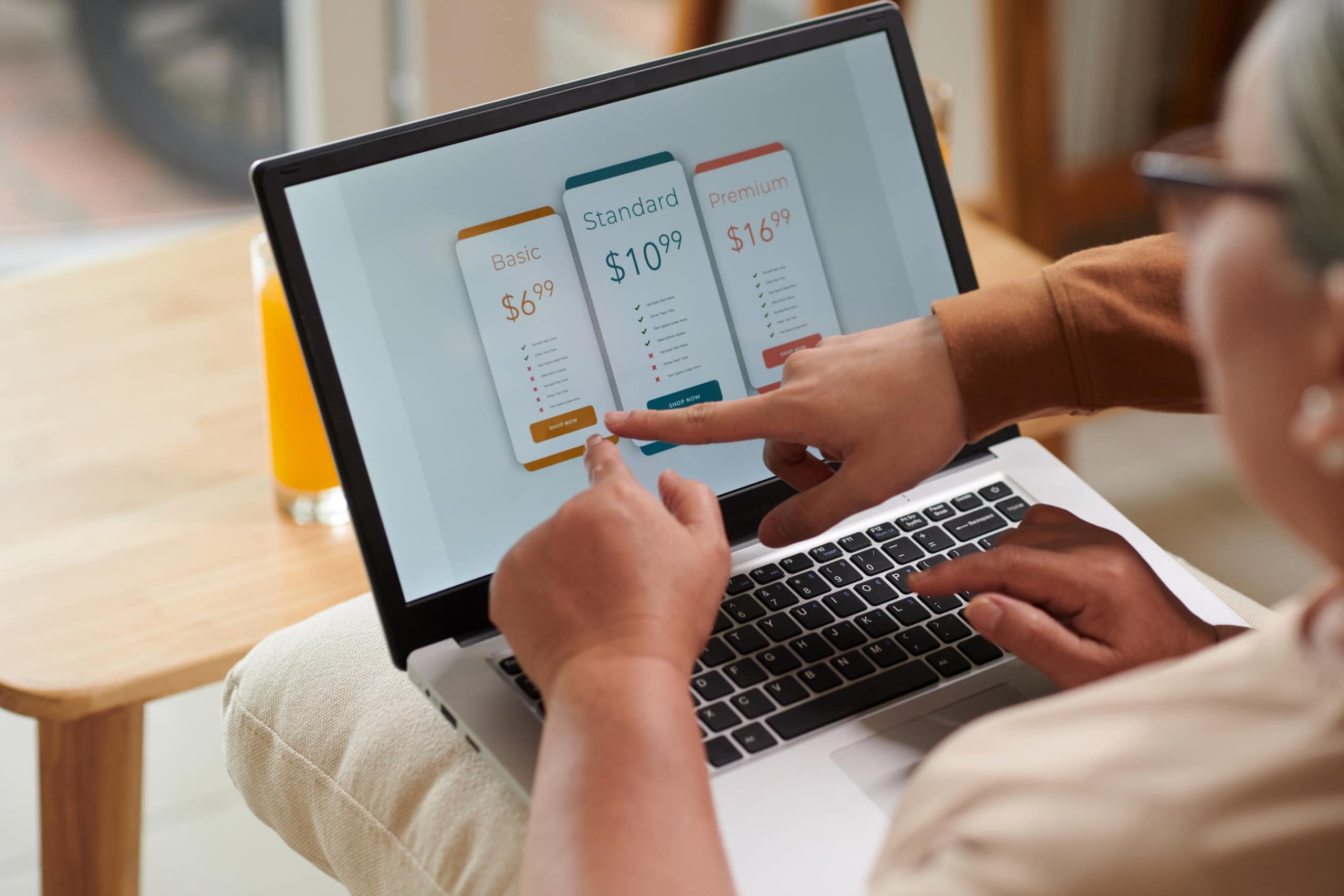 Woman pointing to her laptop screen that shows 3 different subscription plans