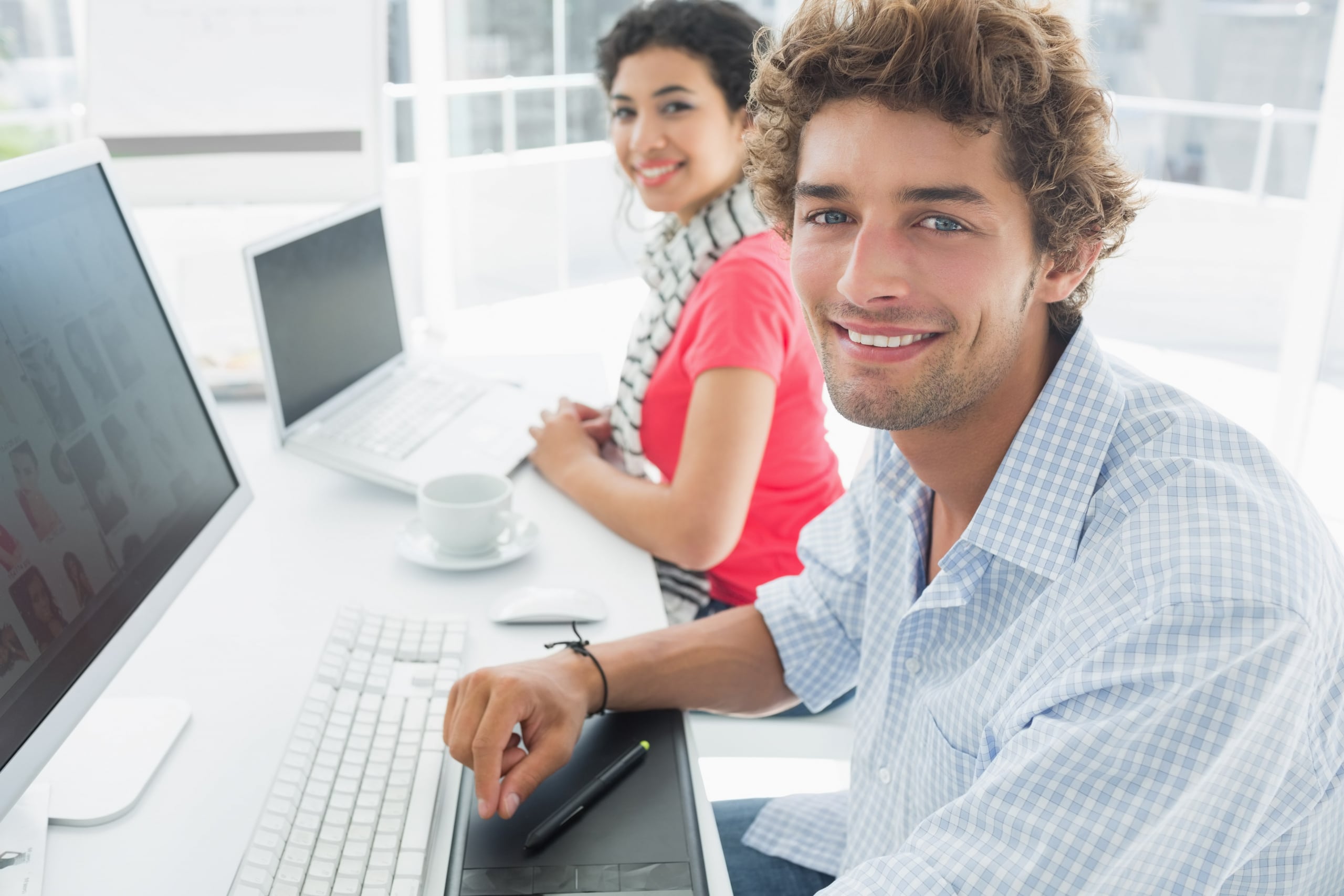 Male and female co-workers working at the computers smiling