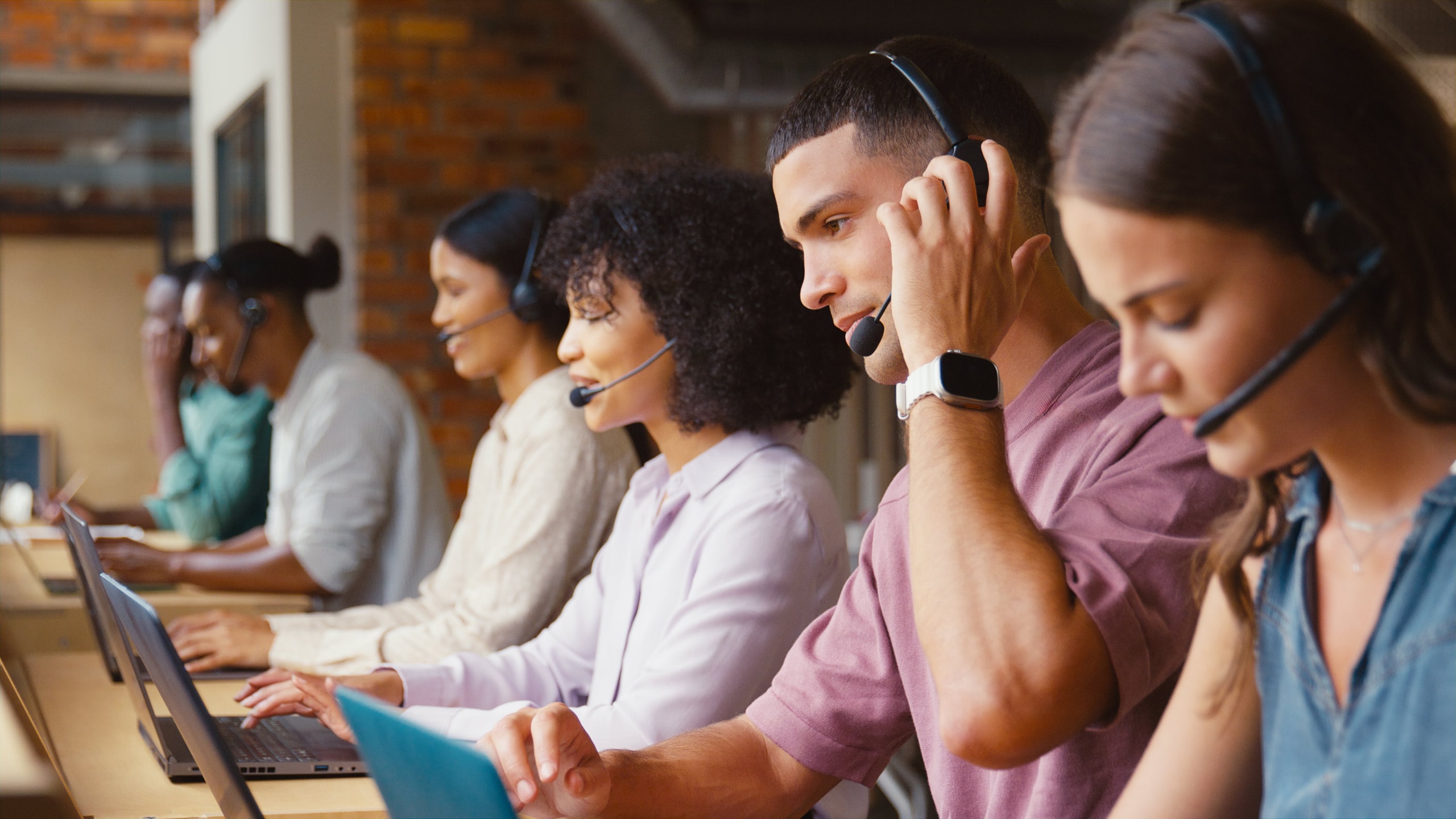 Group of nearshore call center workers on their computers with headsets on talking to customers