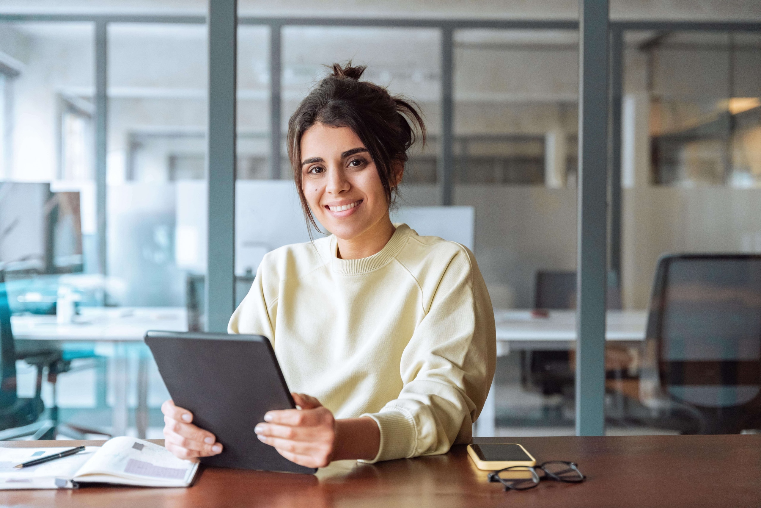 Portrait of middle eastern student or worker using tablet pc financial application standing in office. Smiling indian or latin hispanic business woman holding digital pad computer, looking at camera.