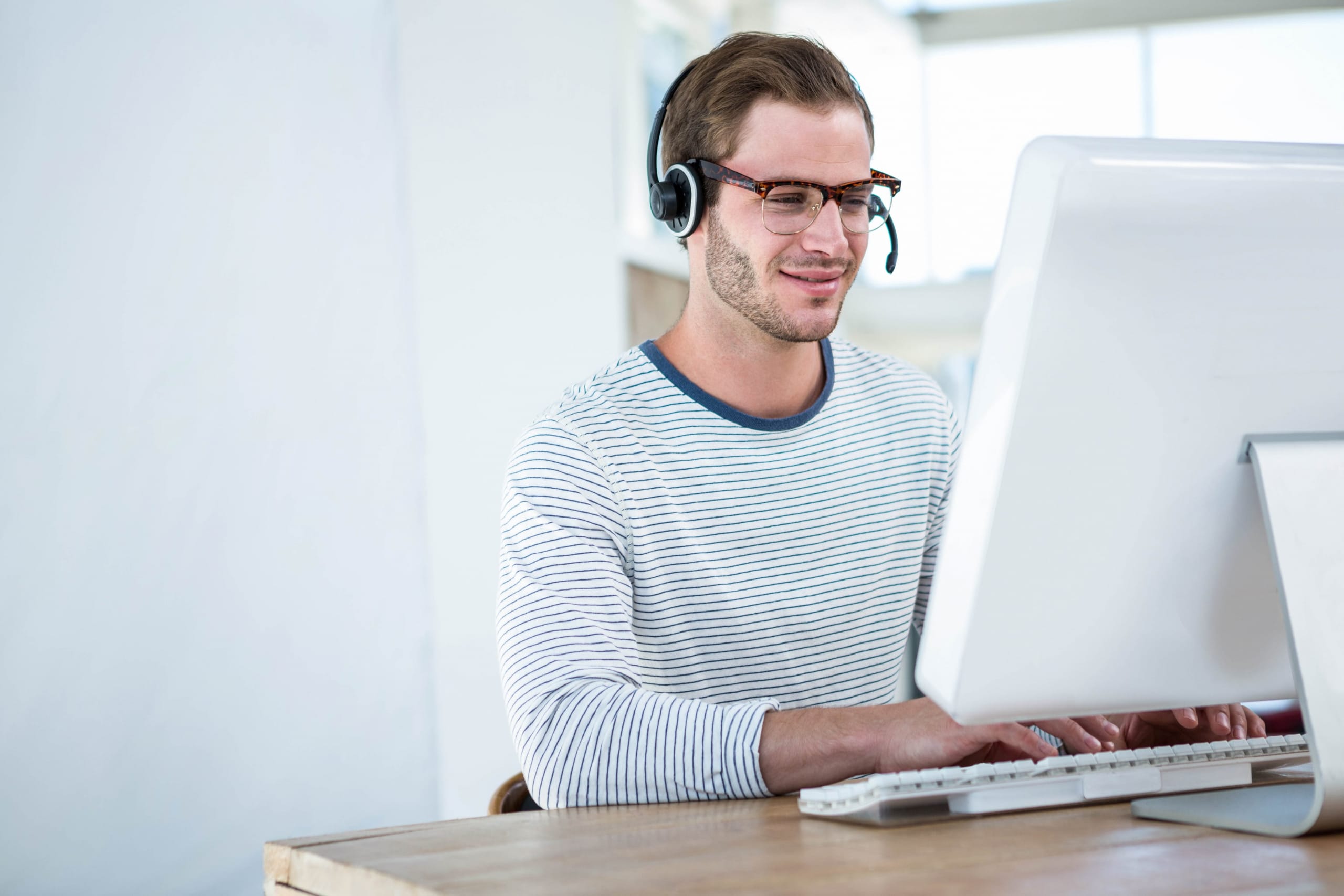 Male inbound call center worker on his computer with headset