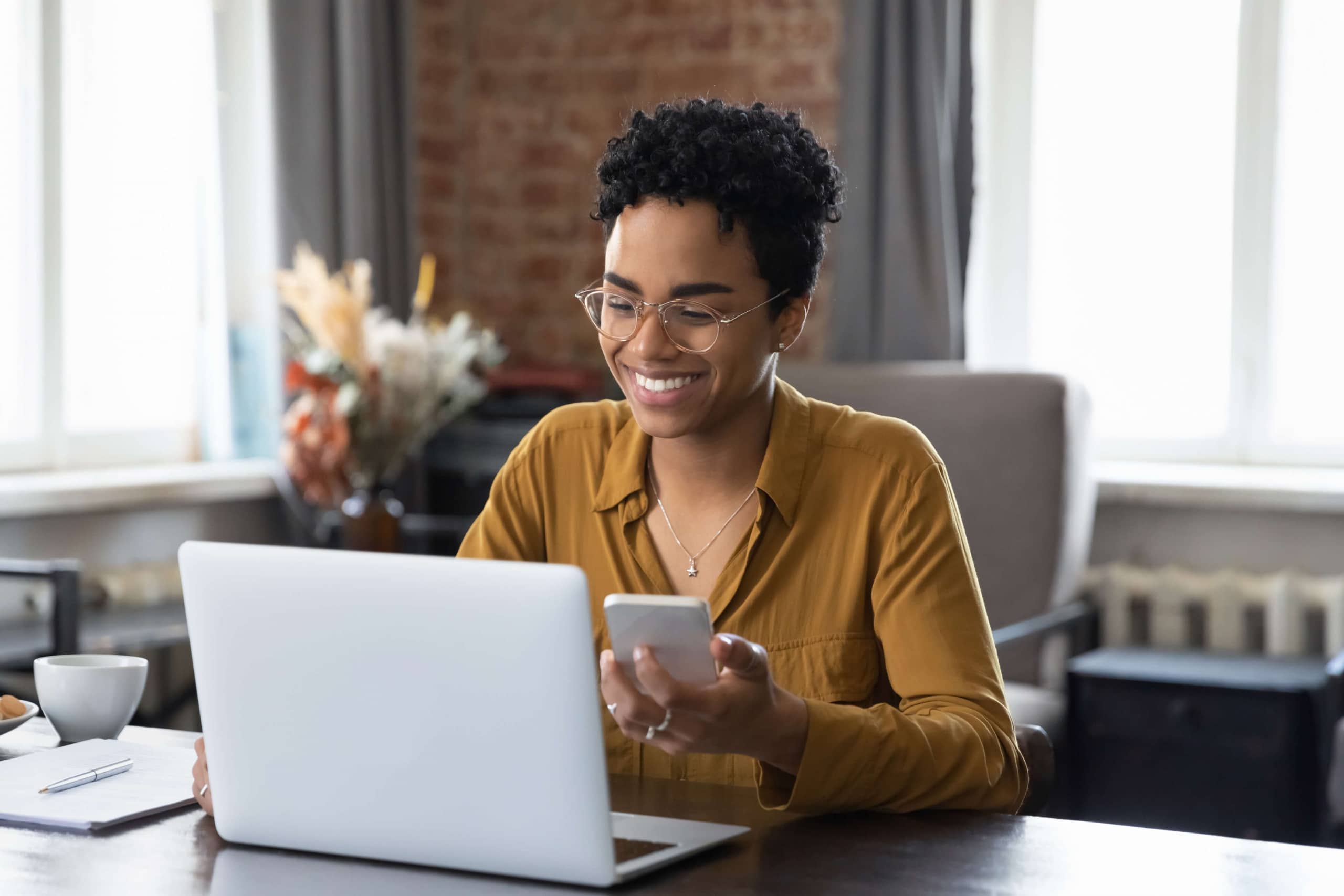 Young Latin woman on her phone and sitting at her laptop