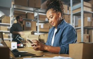 african american woman on her phone in an ecommerce warehouse
