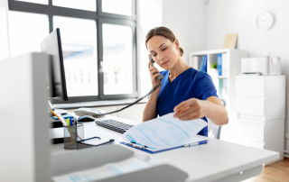 female nurse on the phone at a computer looking at reports
