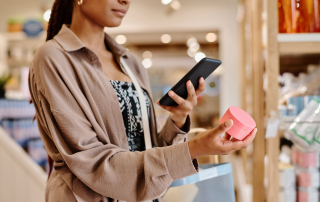 female retail shopper checking the price of makeup on her phone in a retail store