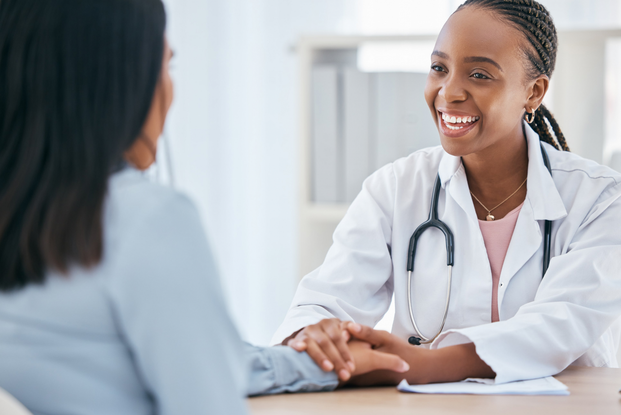 female doctor holding a patient's hand and smiling