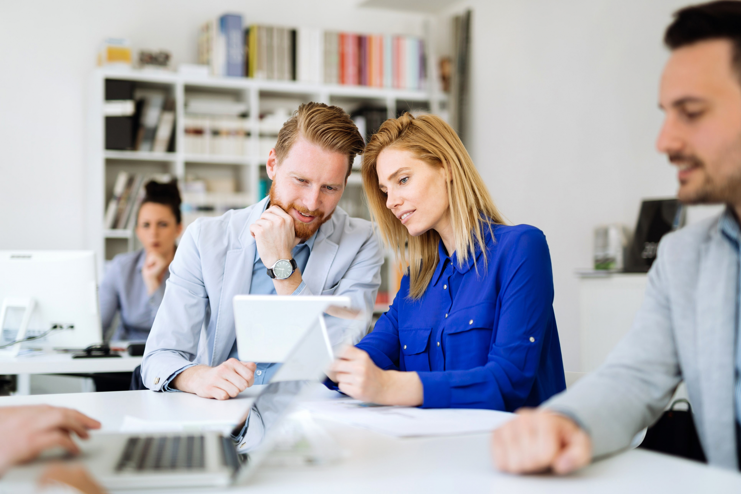 male and female coworkers looking at a tablet and strategizing