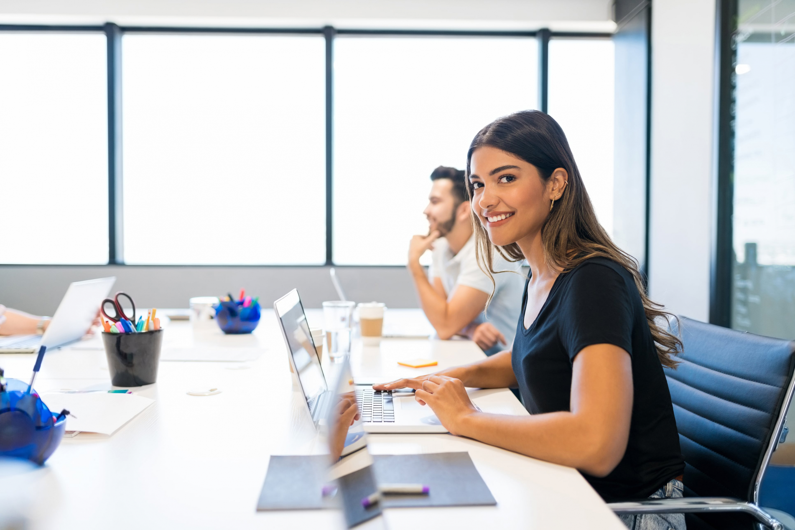 young hispanic female office worker typing on her laptop smiling