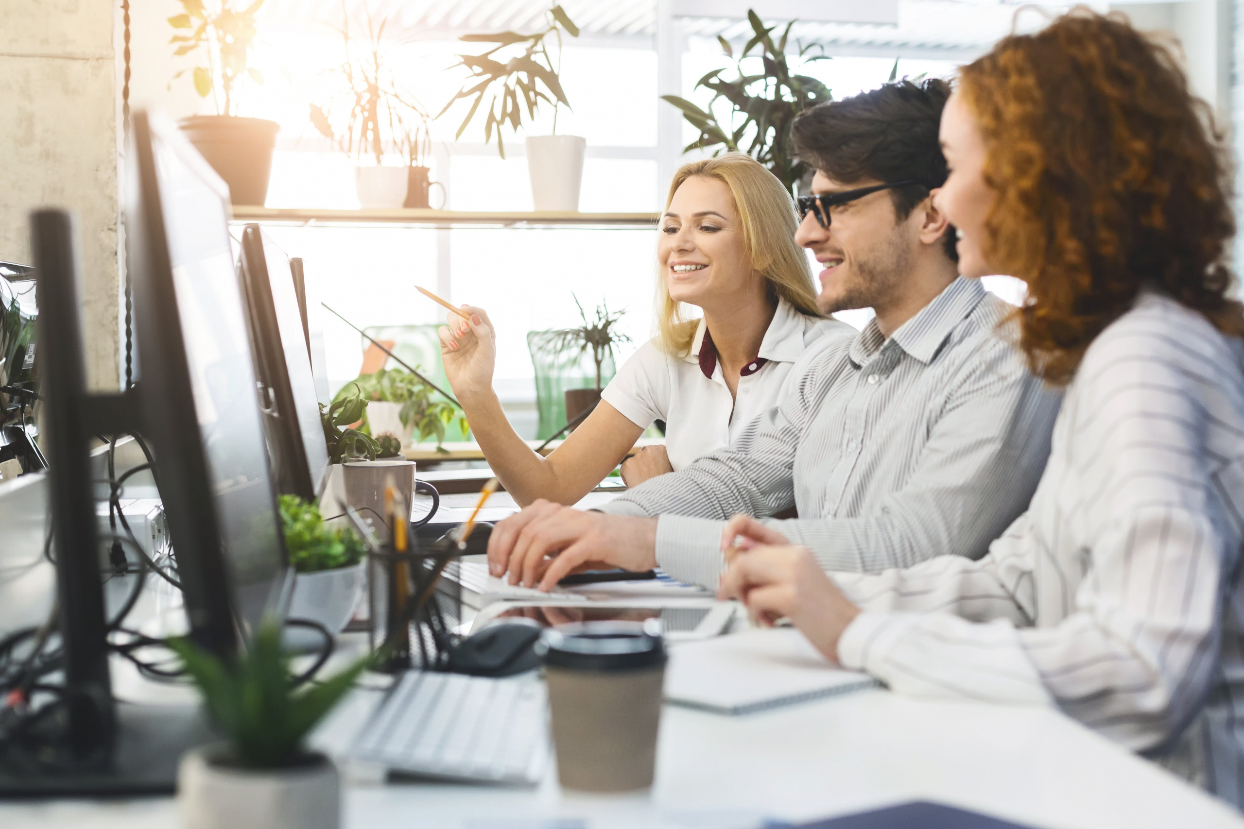 3 co workers talking and looking at a computer screen