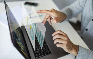 A person working at their laptop with virtual windows of graphs and data.
