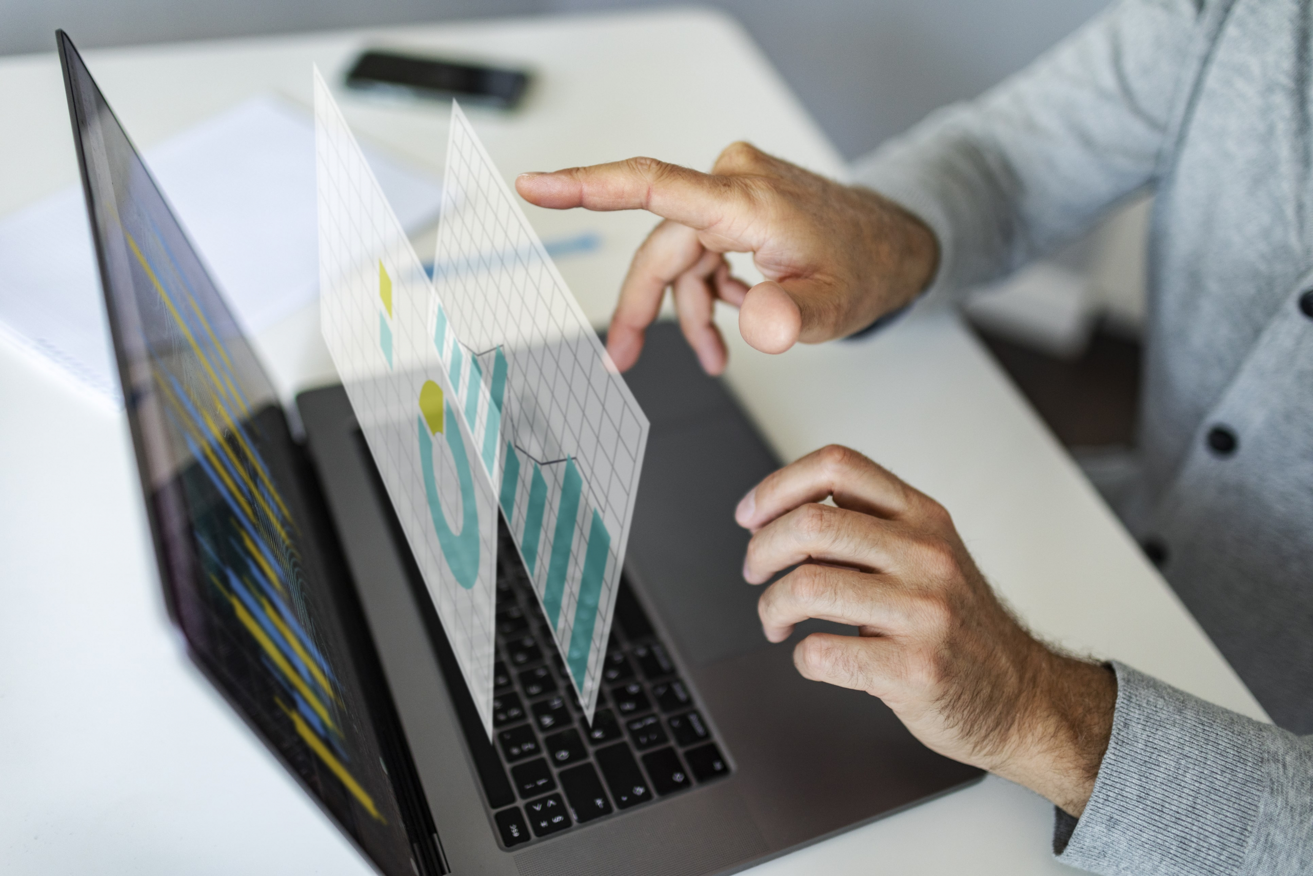 A person working at their laptop with virtual windows of graphs and data.
