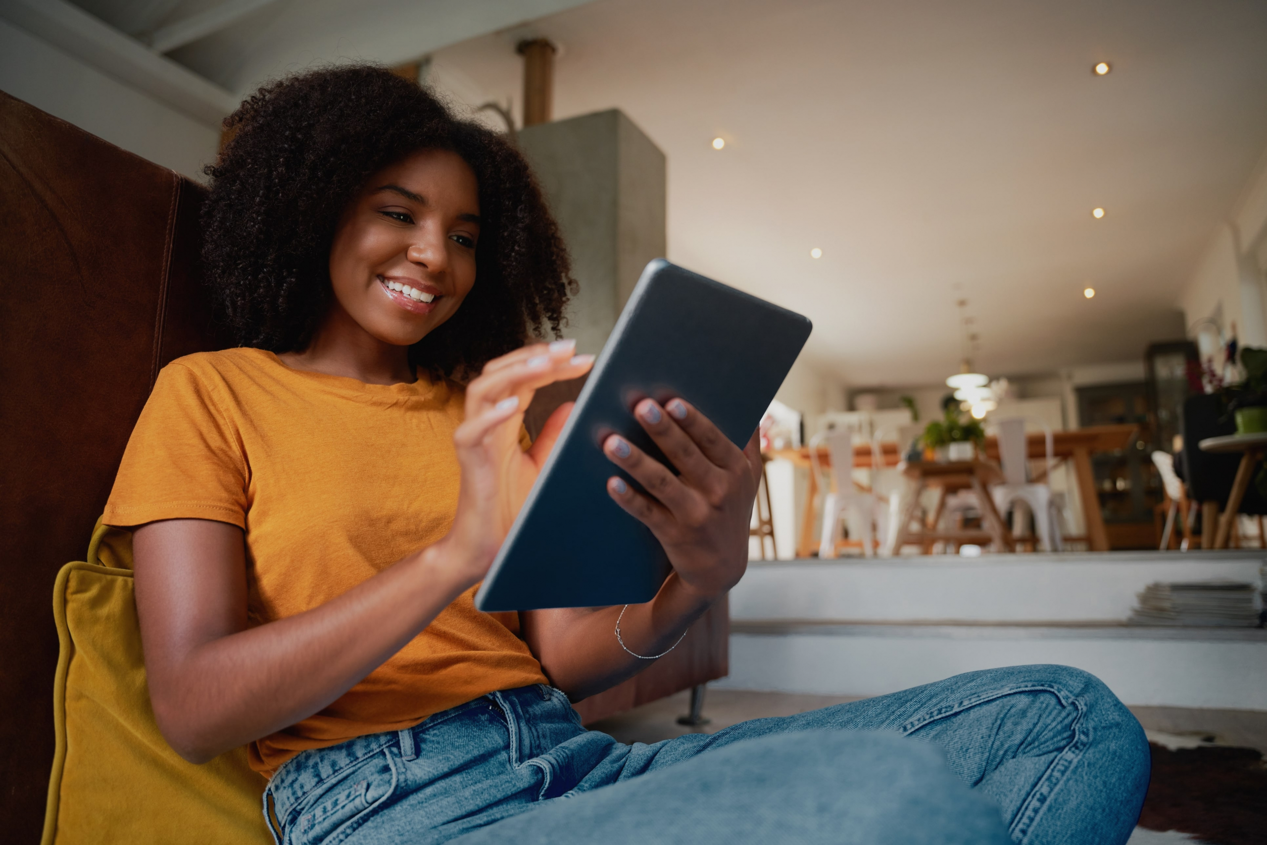 young african american woman sitting on a couch with a tablet