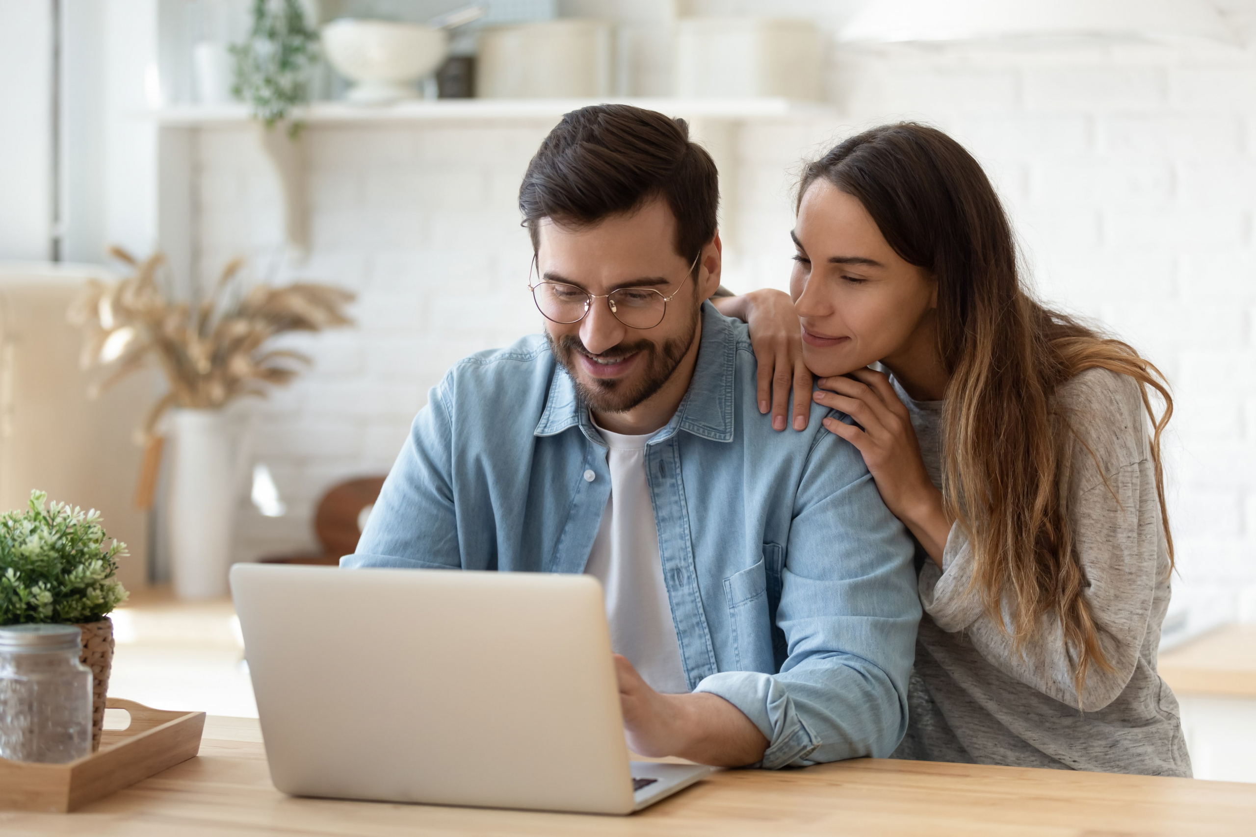 young couple smiling looking at a laptop