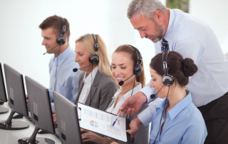 Customer support representatives on the phone and their manager showing them performance charts.