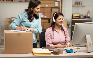 Two female customer service specialists at a computer helping out with ecommerce customer support.
