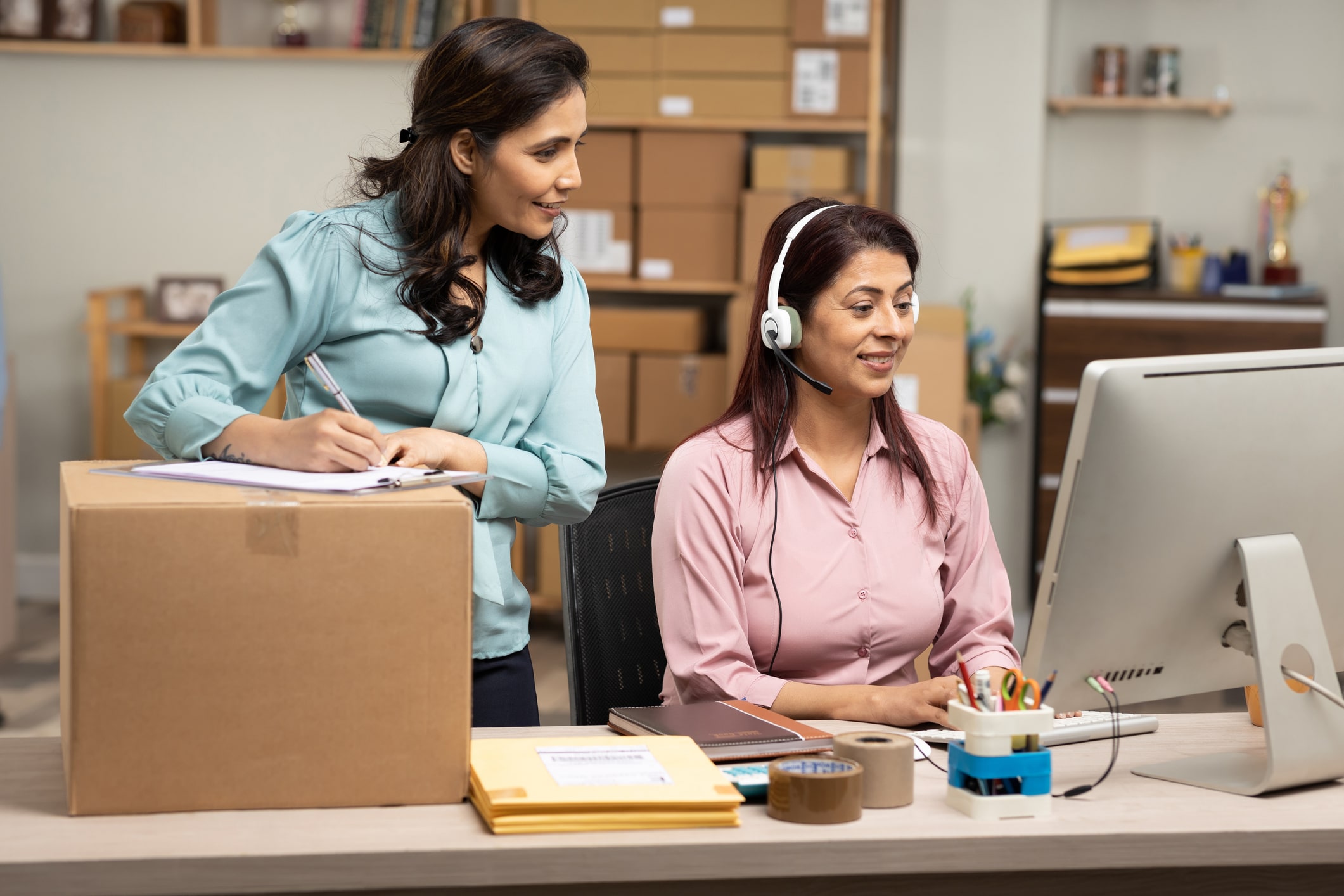 Two female customer service specialists at a computer helping out with ecommerce customer support.