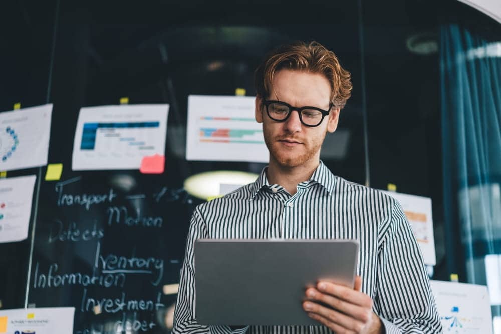 male with a beard looking at an ipad